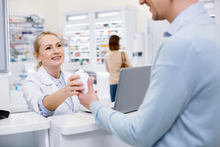 Try this. Attractive female pharmacist assisting man and looking at himの写真素材