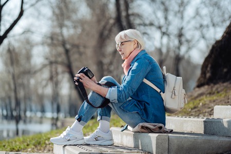 Nice photos. Alert mature woman sitting on the steps and looking through photosの写真素材