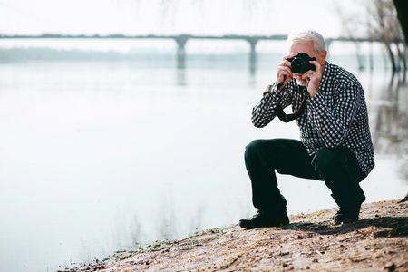 Time to experiment. Creative mature man sitting down and taking picturesの写真素材