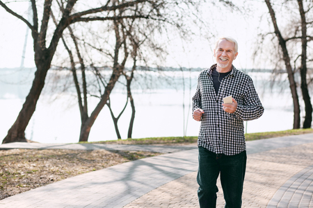 Clean air. Vigorous senior man running and listening to musicの写真素材