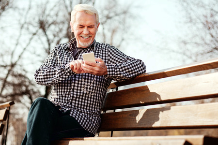Song after song. Low angle of jolly senior man staring down and listening to musicの写真素材