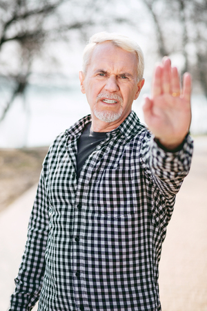 Pull up. Dissatisfied senior man standing in park and demonstrating handの写真素材