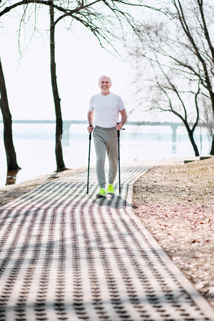 Foot race. Energetic mature man practicing race walking in park while enjoying weatherの写真素材