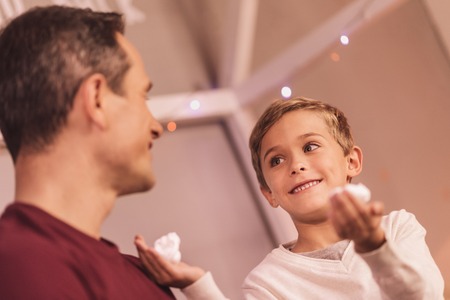 Time for fun. Positive nice delighted boy looking at his father and smiling while holding shaving foam in his handsの写真素材