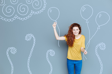 Wonderful party. Cheerful excited young mother holding balloons while organizing a party for her childの写真素材