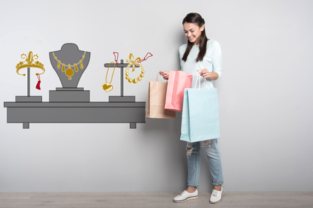 Buying jewelry. Cheerful emotional woman smiling while looking at the new jewelry in her purchasesの写真素材