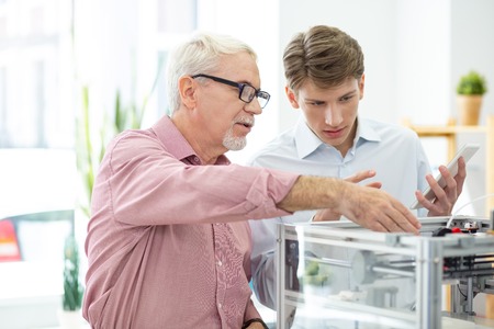 Helpful information. Caring senior engineer helping his young intern and telling him about their new...