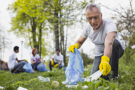 Precious nature. Concentrated senior volunteer holding garbage bag and looking at cameraの写真素材