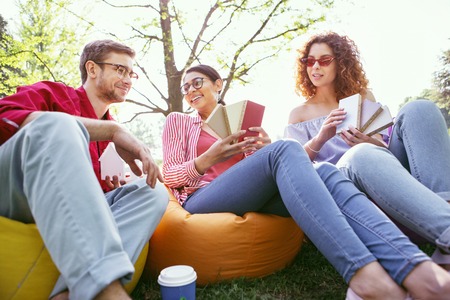 Feeling inspired. Joyful dark-haired woman sitting in the open air with her co-workers and discussing their startupの写真素材
