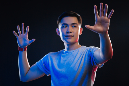 Amazing technology. Nice positive man holding his hands up while pressing them to the virtual screenの写真素材