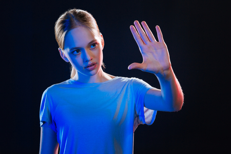 Smart technology. Nice young woman looking at her hand while touching the sensory screenの写真素材