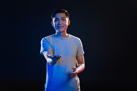 Digital technology. Positive joyful man holding his smartphone while smiling to youの写真素材