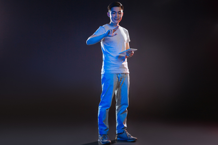 Positive mood. Delighted positive man looking at his finger while holding a tablet