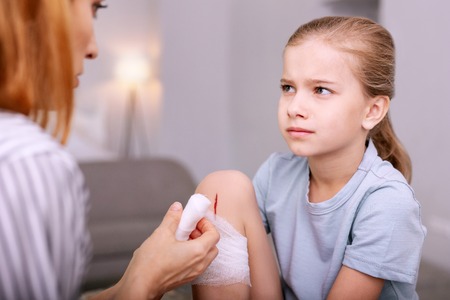 My wound. Depressed young girl looking at the nurse while feeling painの写真素材