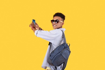 Young traveler. Pleasant handsome man turning to you while holding a smartphone in his handsの写真素材