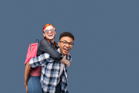 Having fun. Joyful happy man carrying his friend while having fun with herの写真素材