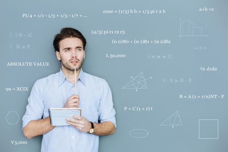 Difficult geometry. Calm clever student touching his lip with a pencil and thoughtfully looking into the distanceの写真素材
