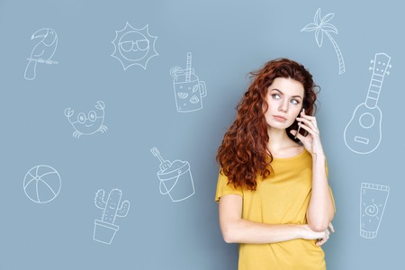 Talking on the phone. Peaceful young woman standing alone and looking calm while talking on the...