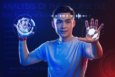 Futuristic technologies. Experienced clever web developer feeling impressed while having hologram images on his handsの写真素材