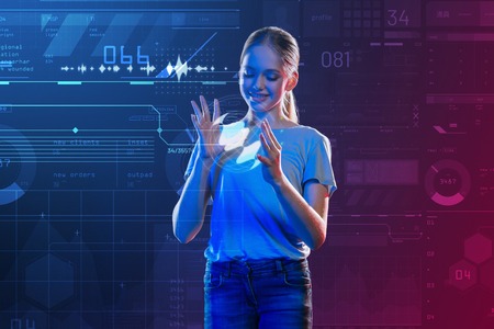 Progressive pupil. Positive clever schoolgirl feeling interested while having an exciting lesson and creating a hologramの写真素材