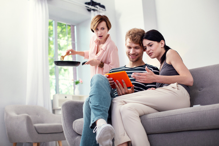 Pleasant communication. Joyful positive couple looking at the tablet screen while discussing a pictureの写真素材