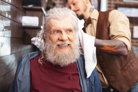 Joyful mood. Pleased mature man keeping smile on face while looking asideの写真素材