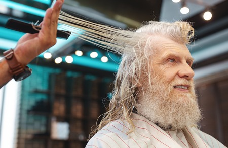 I like it. Pleased bearded man keeping smile on face while enjoying procedure in salonの写真素材