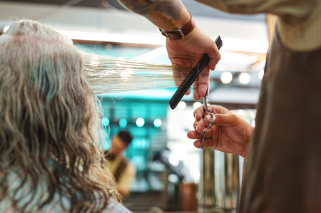 Precious worker. Delighted elderly customer sitting in semi position while communicating with hairdresserの写真素材