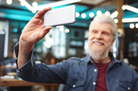 My choice. Delighted senior man keeping smile on his face while having online communicationの写真素材