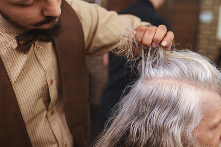 Cut hair. Professional barber bowing head while standing in semi positionの写真素材