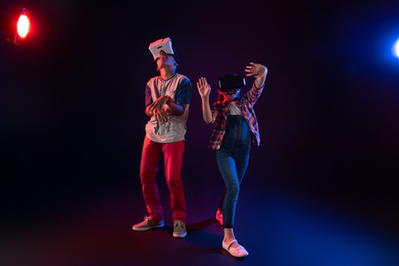 Our recreation. Exuberant lovely girl and a boy wearing VR headsets and playing togetherの写真素材