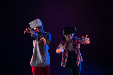 Great time together. Delighted sweet girl and a boy wearing VR headsets and playing togetherの写真素材