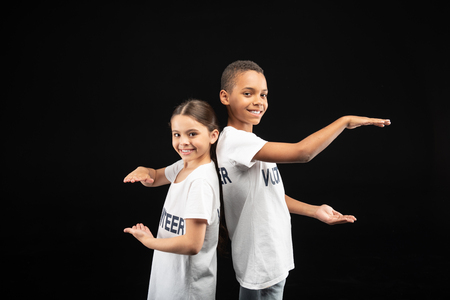 Teamwork. Cheerful cute young volunteers wearing white shirts and showing the sizeの写真素材