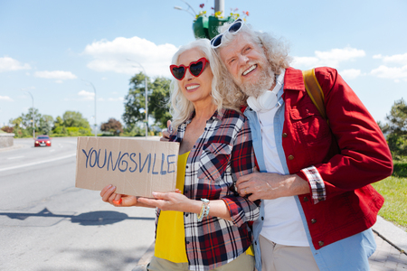 On the road. Delighted positive couple standing together at the roadside while travellingの写真素材