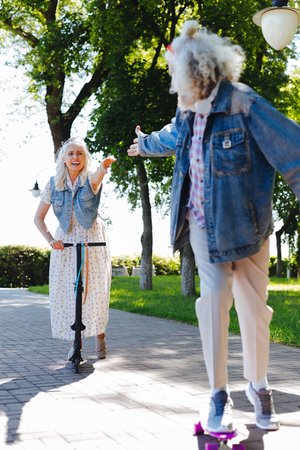 Follow me. Nice positive man giving his hand to his wife while skatingの写真素材