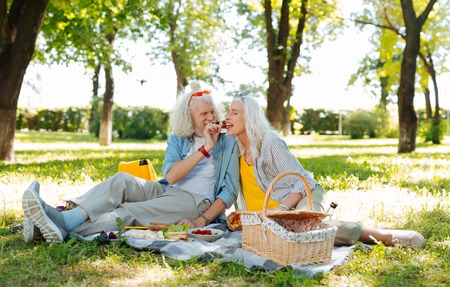 Sweet and tasty. Delighted cheerful woman sitting together with her husband while trying delicious foodの写真素材