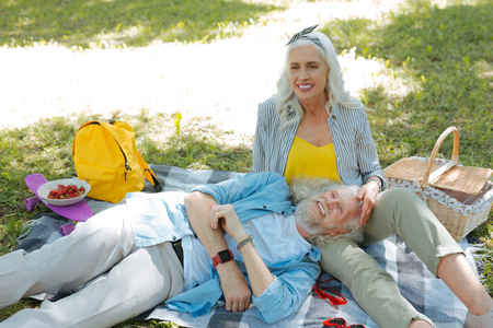 Together with wife. Nice cheerful man feeling happy while being together with his wife on a picnicの写真素材
