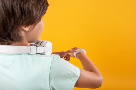 So smart. Intelligent dark-haired boy thinking and looking at his watchの写真素材