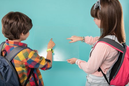 New possibilities. Alert curious kids standing next to each other and holding a screenの写真素材