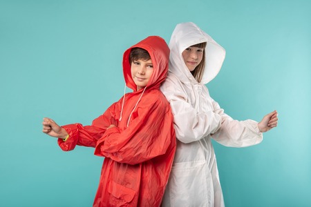 Great clothes. Content sweet kids standing next to each other and wearing raincoatsの写真素材