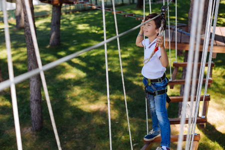 Little adventure. Cheerful preteen boy walking along a trail in a rope park and smiling happily, enjoying his little adventureの写真素材