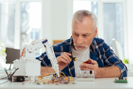 Favourite occupation. Serious smart engineer making a robot while working on his projectの写真素材
