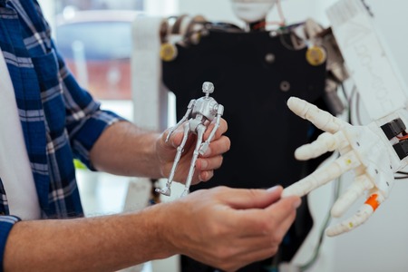 Futuristic tech. Close up of a robot model being in hands of a smart genius engineerの写真素材