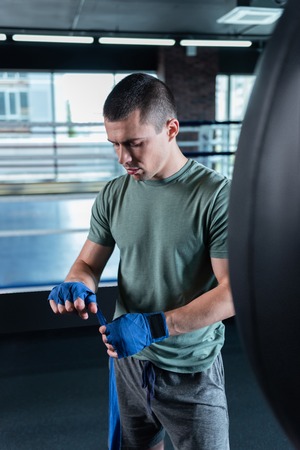 Dark-haired sportsman. Dark-haired handsome promising sportsman standing near punching bagの写真素材