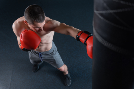 On steroids. Athletic man on steroids wearing no shirt feeling busy while working hard with punching bagの写真素材