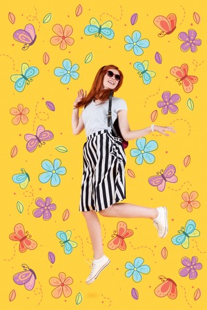 Jumping high. Positive expressive young girl jumping while enjoying the beauty of nature and good weatherの写真素材