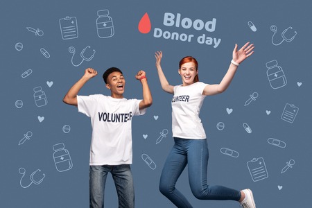 Blood donor day. Positive enthusiastic volunteers jumping and feeling happy while celebrating Blood donor dayの写真素材