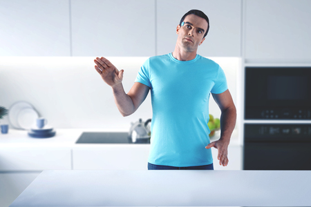 Switched off humanoid. Futuristic useful home humanoid standing in the laconic kitchen with his hands up while being switched offの写真素材