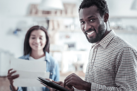 Digital device. Cheerful handsome positive man holding a tablet and looking at you while being in a great moodの写真素材