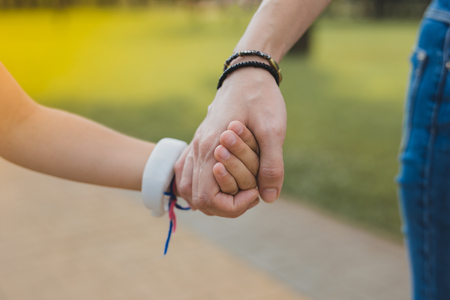 Black bracelet. Loving modern mother wearing black bracelet holding her daughter walking in the park togetherの写真素材